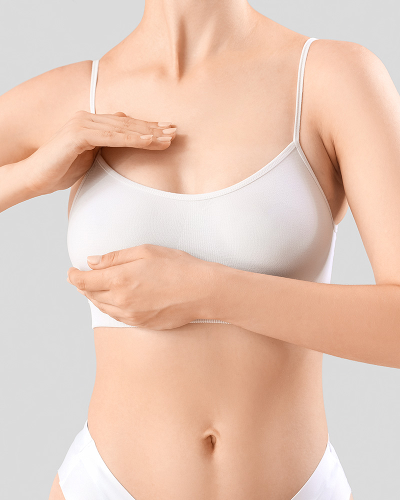 Woman in a white bra holding her breast